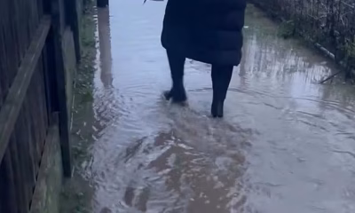 Parents carry their children to school through muddy water ’caused by monstrous 60ft tall warehouse’ – as council promises to dig a ditch ‘as soon as weather permits’