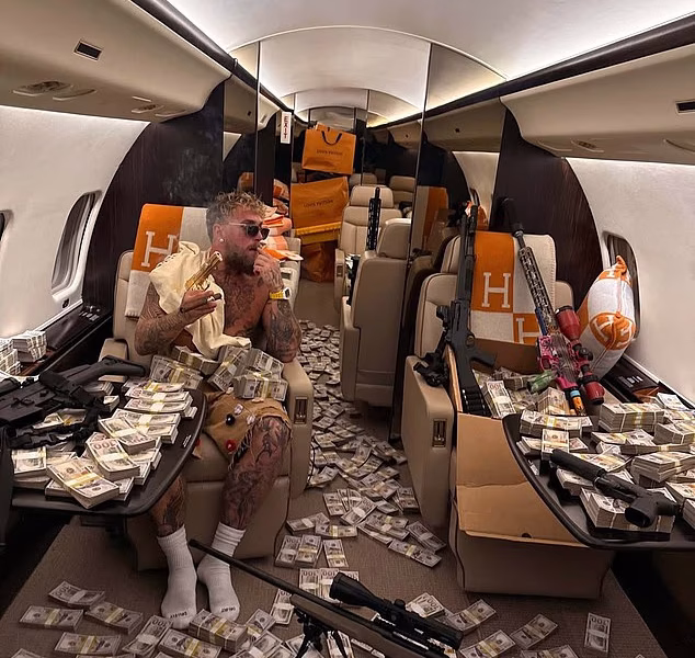 Worth the jaw break, Jake? Battle-scarred Paul flaunts £140m purse after knockout defeat to Anthony Joshua – posing with wads of cash and SIX guns on a private jet